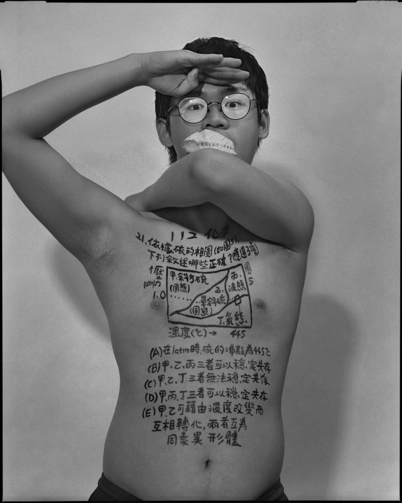 《答案》系列：黑白肖像，正面軀幹寫滿〈化學，2023〉考題手寫文字，口中塞著紙捲，雙手於臉部前交疊。