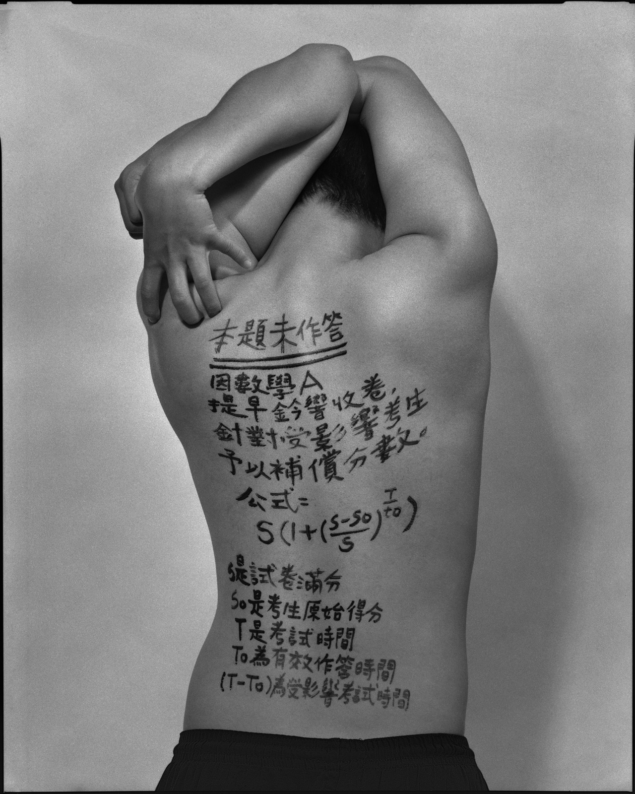 《答案》系列：黑白肖像，背面軀幹寫滿〈數學，2022〉考題手寫解答，雙手於頸後或背後交扣。
