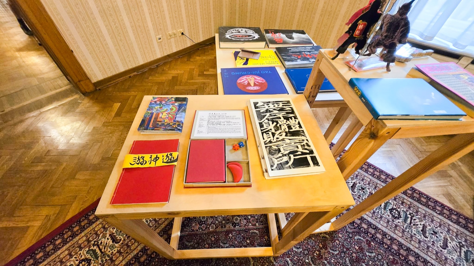 《複眼之島》羅茲展場：木質展桌上陳列臺灣藝術家手工書，中央為《無序身體販賣所》經摺裝，攝於 Art_Inkubator。