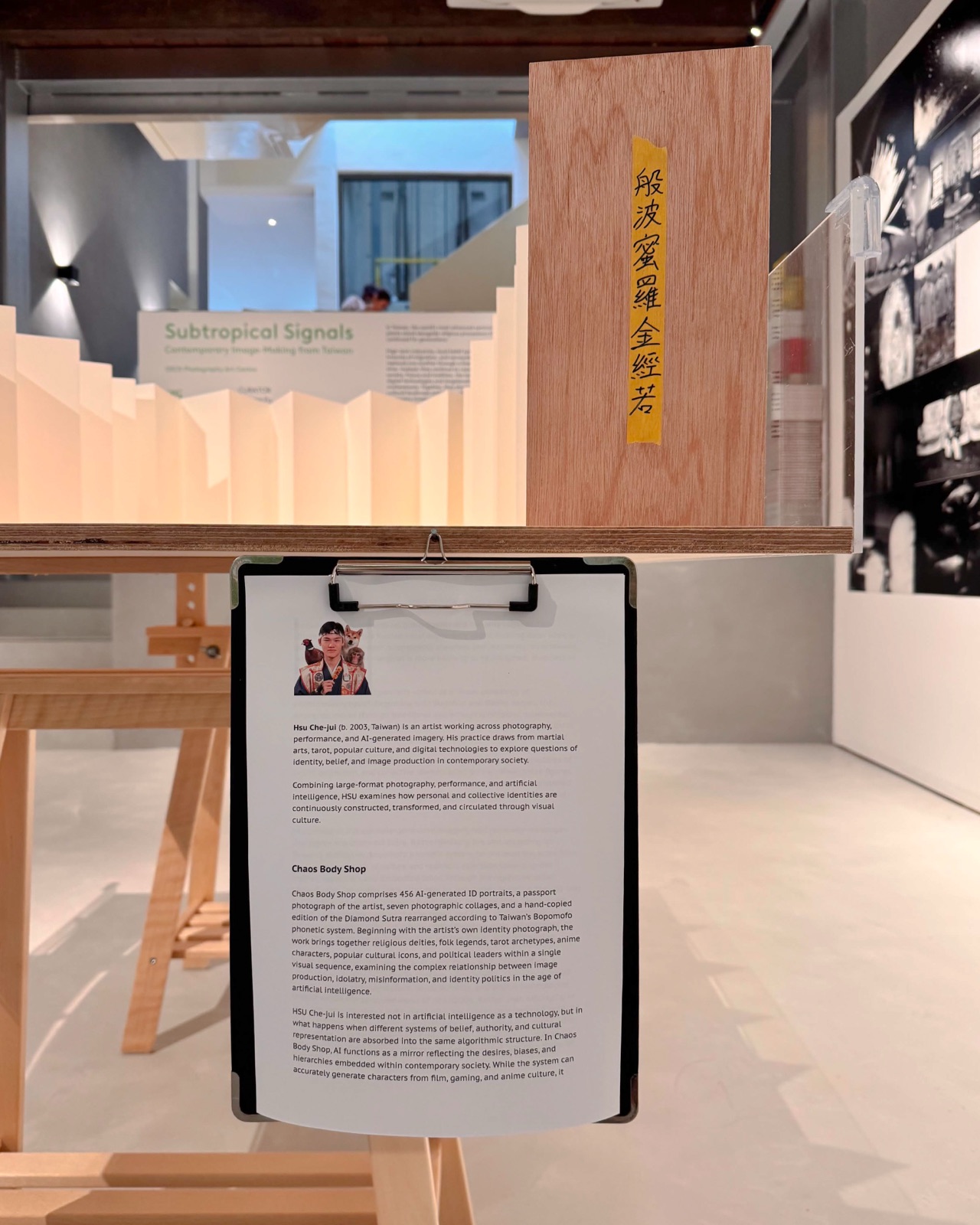 《亞熱帶訊號》展場局部：《無序身體販賣所》木質書名籤「般波蜜羅金經若」與夾板藝術家介紹，經摺裝側緣。